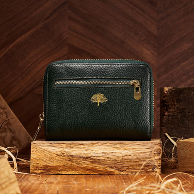 green leather purse with gold engraved tree emblem and gold zip detailing 